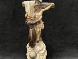 une statue représentant un homme tenant une croix, posée sur un socle