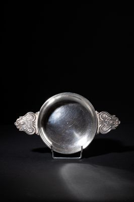an antique silver plate on a stand against a black background