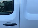 une camionnette blanche dont la portière est ouverte et où un chien est assis sur le siège passager