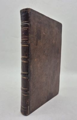 an old book sitting on top of a white table next to a white wall