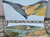 deux tableaux représentant un paysage, posés sur un sol en briques près d'un mur