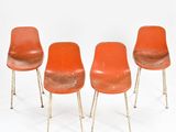 trois chaises orange placées les unes à côté des autres sur une surface blanche