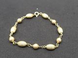 a gold bracelet with beads on a black background