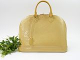 yellow louis vuitton handbag with green plant on white background