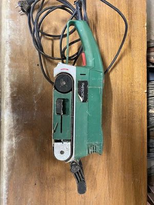 a green and black electric tool on a wooden table