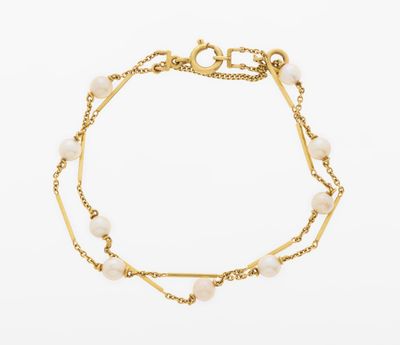 a close up of a gold bracelet with pearls on a white background