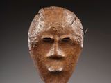 un gros plan sur une sculpture représentant un visage posée sur une table