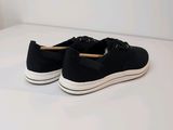 black sneakers with white soles on a white surface