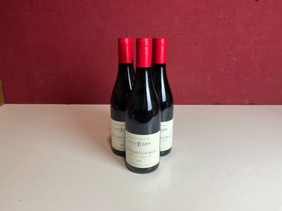 Deux bouteilles de vin sont posées sur une table devant un mur rouge.