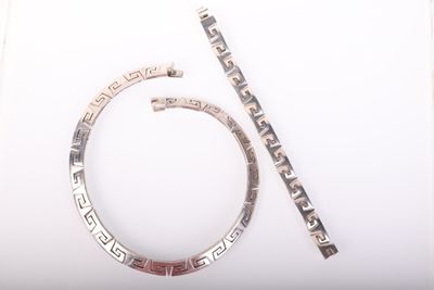 deux bijoux en argent posés sur une surface blanche, à côté d'une paire de ciseaux