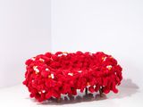 un bol rouge au crochet posé sur une surface blanche