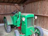 un tracteur vert garé dans une grange aux murs en bois