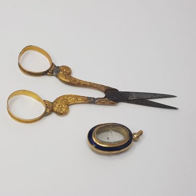 a pair of scissors and a pocket watch sitting on a table