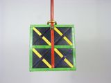 a green and yellow ornament hanging from a red string