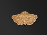 une assiette en or sur laquelle figure une inscription en chinois, posée sur un fond noir