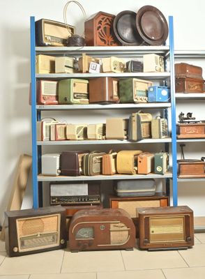 beaucoup de vieilles radios posées sur une étagère dans une pièce