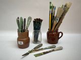 de nombreux pinceaux et un pot de peinture sur la table