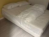 a bed that has a white comforter on it in a room