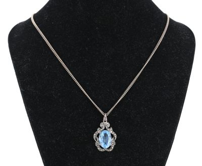 un collier avec une pierre bleue et une chaîne en argent sur un mannequin
