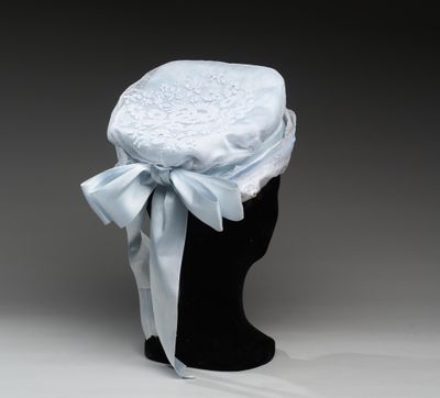 un chapeau blanc orné d'un ruban bleu et d'un nœud, posé sur la tête d'un mannequin
