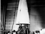 une vieille photo en noir et blanc montrant un groupe de personnes rassemblées autour d'une fusée spatiale
