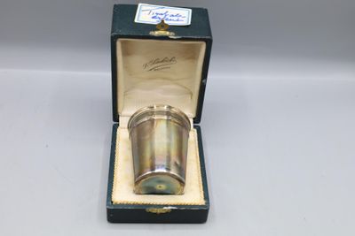 une coupe ancienne en métal argenté, dans un coffret posé sur une table