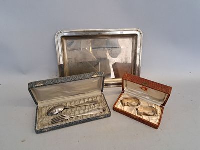 trois pièces d'argenterie dans un coffret en argent posé sur une surface blanche