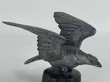 statue of a flying bird on a marble base on a white background