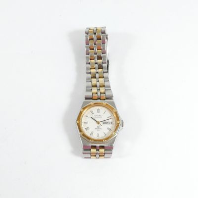 une montre argentée et dorée posée sur une surface blanche
