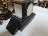 a small clock sitting on a table next to a lamp