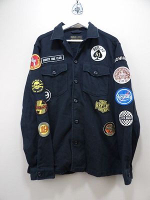 une veste en jean ornée de patchs, suspendue à un cintre