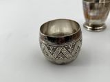 two silver cups sitting on top of a table next to each other