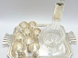 a silver tray with a glass decanter and silver cups