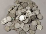 une pile de pièces de monnaie posée sur une table à côté d'un téléphone portable