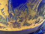 a close up of a blue vase with a gold decoration on it
