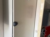 a metal door with a red handle in a room