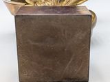 a small gold plant in a square vase on a table