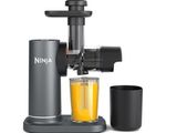 un gros plan d'un extracteur de jus avec un verre de jus à côté