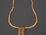a gold necklace with fringes and beads on a gray background