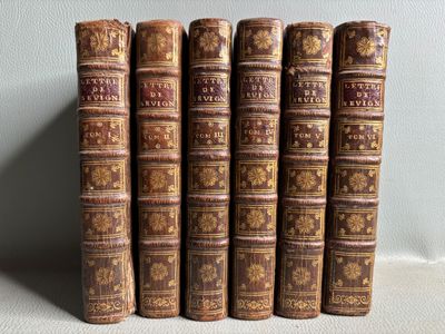 cinq vieux livres sont alignés les uns à côté des autres sur une étagère