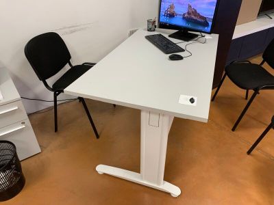 un bureau blanc sur lequel se trouve un ordinateur, avec une chaise noire devant