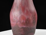 a red vase sitting on a table with a black background