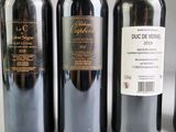 three bottles of red wine are lined up on a table