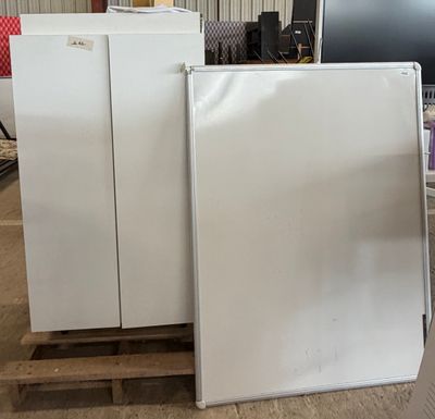two white refrigerators sitting on a pallet in a warehouse