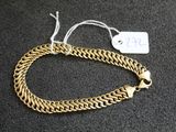gros plan d'un bracelet en chaîne en or sur une surface noire