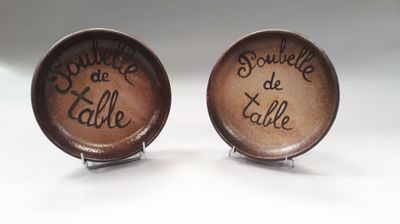 two brown cufflinks with writing on them sitting on a white surface
