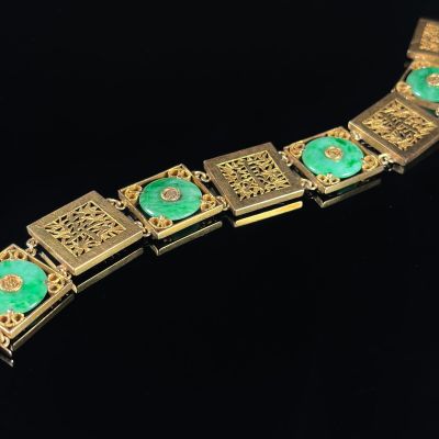 a gold bracelet with green stones