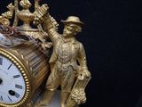 a gold clock with a man and a woman on it