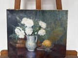 une photo d'un tableau posé sur un chevalet, avec un vase de fleurs
