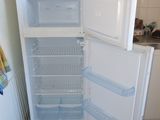 an open refrigerator in a small kitchen with a microwave on top of it